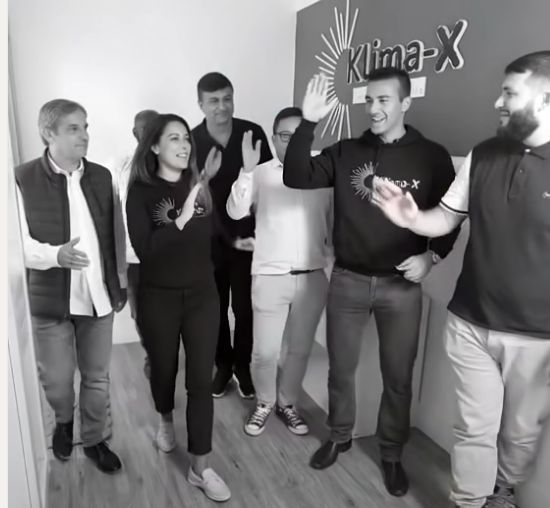 Un groupe de personnes réunies devant le logo Klima-X, extrait de la vidéo de présentation